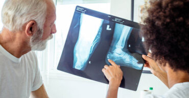 Observa-se uma ortopedista explicando para um paciente as categorias de osteoporose em idosos.