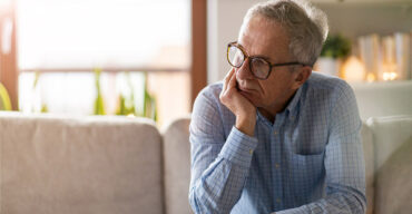 homem de óculos sentado pensando nos problemas de visão em idosos