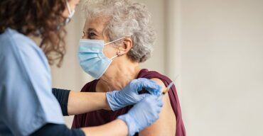 Médica aplicando vacina em mulher idosa