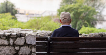 pessoa idosa sentada solitária em um banco na praça mostra como é a solidão do idoso