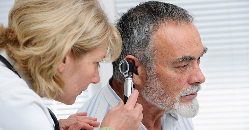 Médica avaliando o ouvido de um paciente idoso