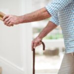 Homem segurando o corrimão. Veja como garantir a segurança de idosos em casa!
