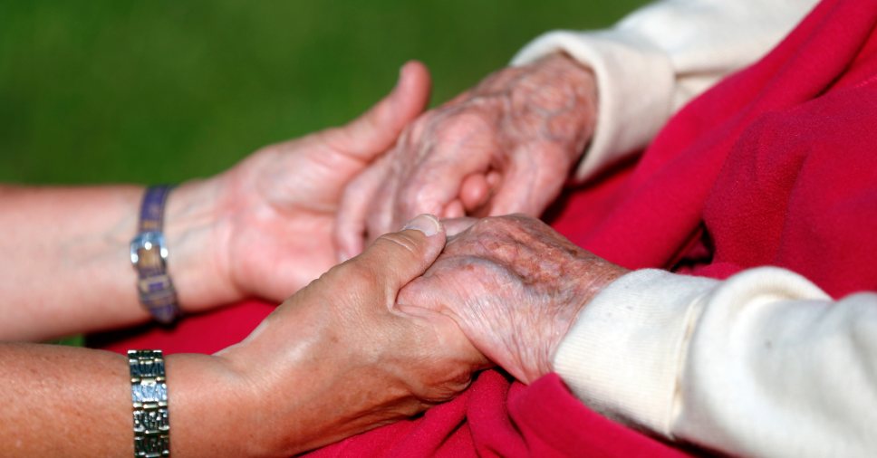 Close de mãos entrelaçadas em sinal de apoio ilustra o cansaço de cuidar dos pais.