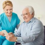 Cuidadora sorridente auxilia homem idoso a usar smartphone em inclusão digital do idoso.